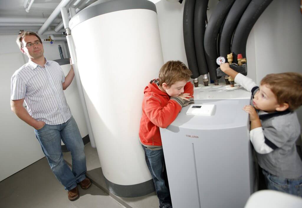 father and sons looking at heat pump
